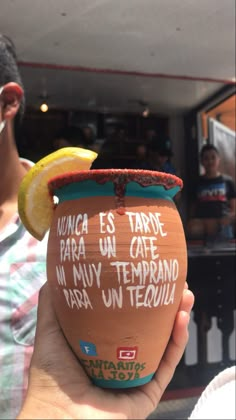 a person holding up a cup with writing on it and a lemon in the background