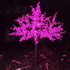 a tree with purple lights on it in the dark