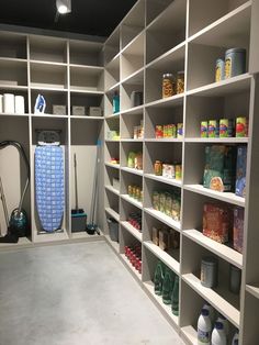 a walk in closet filled with lots of shelves next to a blue vacuum and other items