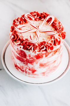 a red and white cake sitting on top of a white plate covered in frosting