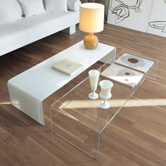 a glass coffee table sitting on top of a hard wood floor next to a white couch