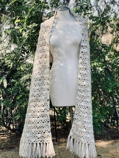 a white crocheted shawl with tassels hanging from it's sides