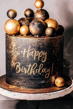 a birthday cake decorated with gold and black balls