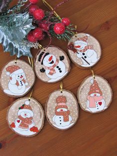 christmas ornaments with snowmen on them sitting on a wooden table next to a tree