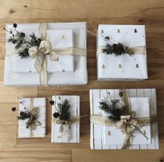 four wrapped presents tied with twine and pine cones on wooden floored area next to each other