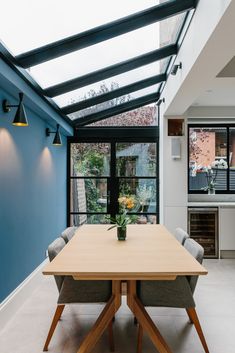 a wooden table sitting in the middle of a room with blue walls and glass windows