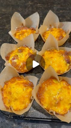 several muffins on a baking sheet ready to be baked in the oven with melted cheese