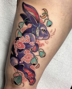 a tattoo with an image of a rabbit on it's leg and flowers in the background