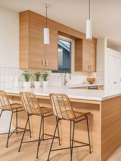 a kitchen with wooden cabinets and bar stools next to an island in the middle