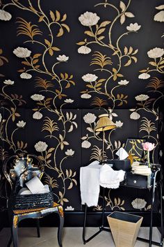 a black and gold wallpapered room with two chairs in front of the table