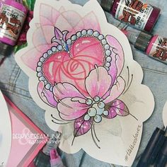 some markers and pens are laying on the table next to an image of a pink flower