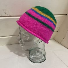 Most of this hat is bright, almost neon pink, with stripes of green and mustard. The end result has a distinctive visual energy to it, as the colors interact with one another in an unusual way. The bottom of the hat has a rolled brim, and the top is smooth and rounded. This hat is structured and handmade. It was knit and felted by hand using 100% secondhand wool yarn in a smoke-free environment. This hat is sized for an adult and suitable for all genders. Enjoy! The hat will arrive in 100% compo Playful Multicolor Short Brim Hat, Fun Pink Beanie Hat, Funky Pink Cap Hat, Playful Pink Beanie Hat, Funky Multicolor Cap, Funky Multicolor Hat With Curved Brim, Playful Multicolor Beanie Hat, Funky Pink Hat With Curved Brim, Fun Green Hat One Size