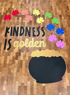 a wooden floor with an image of a pot and clovers on it that says kindness is golden