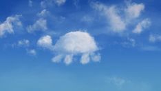 an airplane is flying in the blue sky with white clouds and green grass below it