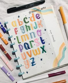 an open notebook with some markers and pens on it