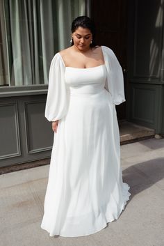 a woman in a white dress is standing outside