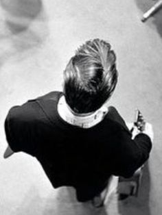 black and white photograph of a woman sitting on the ground with her back to the camera