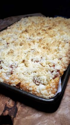 a casserole dish with crumbled toppings sitting on a wooden table