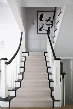 a white staircase with black handrails leading up to the second floor