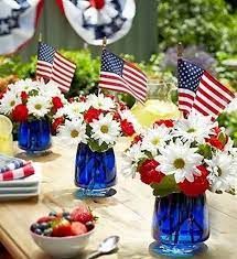 red, white and blue flowers are in vases on a table with american flags