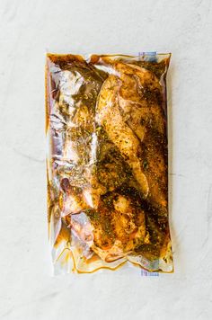 chicken wrapped in foil sitting on top of a white countertop next to a knife and fork