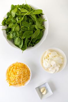 spinach, cheese, and other ingredients are in bowls on a white table top