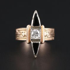 a gold and diamond ring sitting on top of a black surface with an intricate design