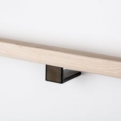 a close up of a wooden shelf on a white wall with a black metal holder