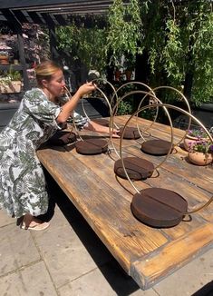 a woman sitting at a wooden table with pots and pans on top of it