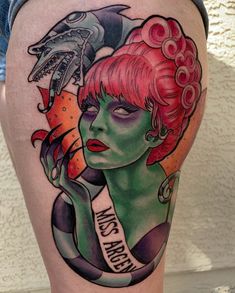 a woman with red hair and tattoos on her thigh is holding a fish in her hand