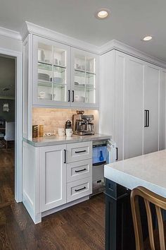 a kitchen with white cabinets and wood flooring, along with a dining room table