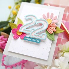 a birthday card with flowers and the number twenty two on it, next to some flowers