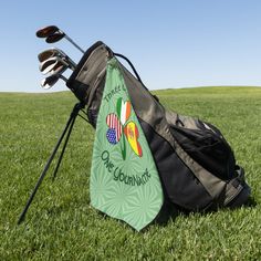 a golf bag sitting on top of a lush green field next to a pair of golf clubs