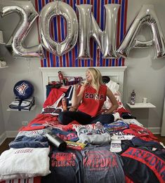 a woman sitting on top of a bed in front of balloons that spell out mom