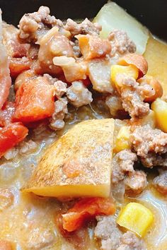 a stew with meat, potatoes and carrots in a black bowl on the table