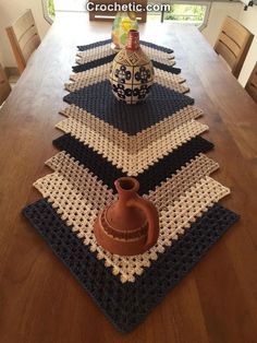 a crocheted table runner with a vase on it