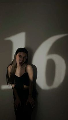 a woman standing in front of a wall with the number six on it's side