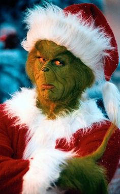 a man dressed as the grinch in a santa suit with his arms crossed and eyes wide open