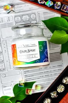 a jar of color spray sitting on top of a table next to some green leaves