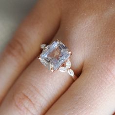 a woman's hand with an engagement ring on top of her finger, showing the center stone