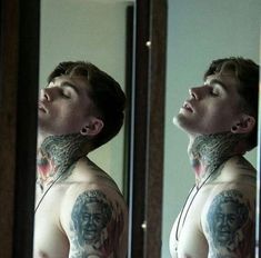 a man with tattoos is looking at himself in the mirror and has his eyes closed