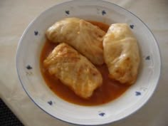 two pieces of food in a bowl on a white tablecloth with blue trimmings