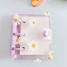 an open binder with daisies on it next to some scissors and other items