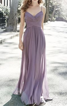 a woman in a long purple dress standing on the street