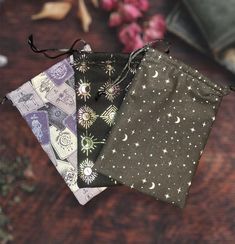 four small bags with different designs on them sitting on a table next to some flowers