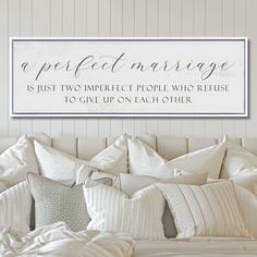 a bed with white sheets and pillows under a sign that says, a perfect marriage is just two imperfect people who refuse to give up on each other