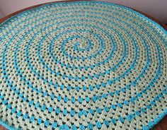 a blue and white crocheted rug on top of a wooden table