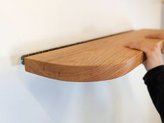 a person is holding onto a wooden shelf