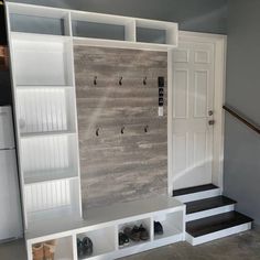 a room that has some shelves and shoes on the floor in front of it, next to a white door