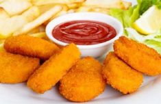 a white plate topped with fried food next to french fries and ketchup sauce